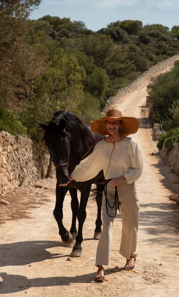 Smiling woman leading a horse over an old portugese road.